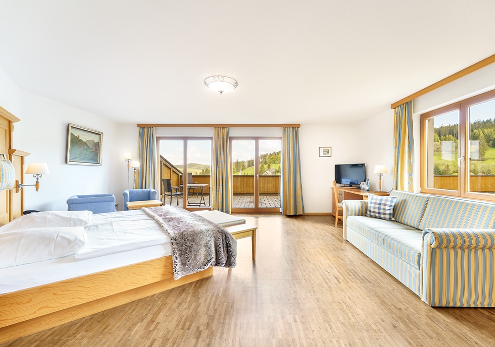 Helles, lichtdurchflutetes Doppelzimmer mit Sofa und Balkon mit Blick auf den Schwarzwald