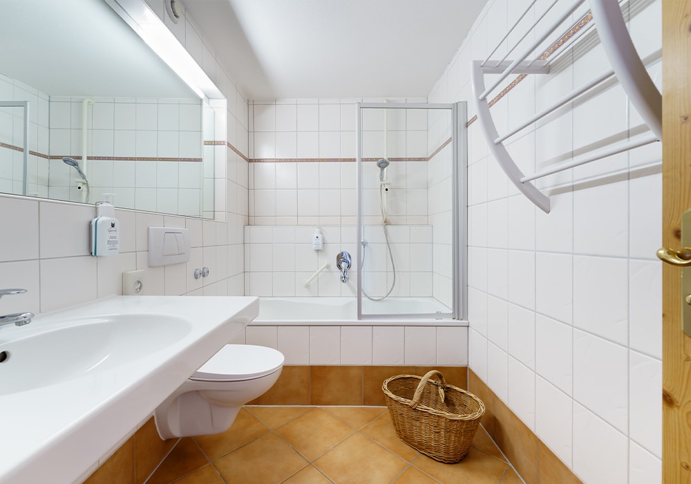 Badezimmer mit Badewanne und großem Spiegel in der Familien Suite Deluxe